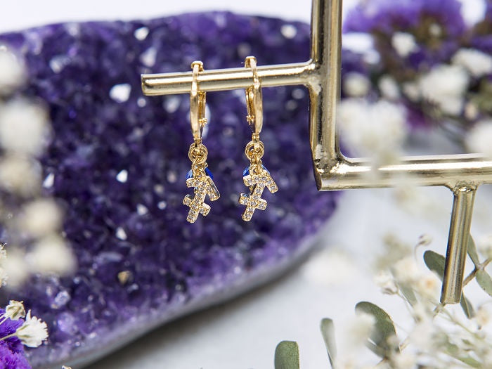 HUGIE DE SIGNO SAGITARIO CON CRISTAL SWAROVSKI MAGENTA, CON CHAPA DE ORO EN 14 KILATES.